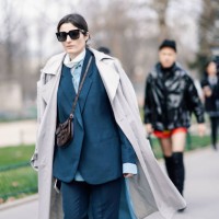 Irina Linovich wears sunglasses, a grey trench coat, a petrol-blue pantsuit, a brown alligator pattern Celine bag, outside Paco Rabanne, during Paris...