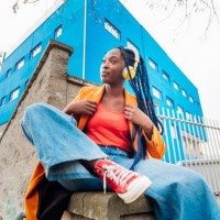 italy, milan, portrait of woman in orange coat against rusty metal fence - fashion stock pictures, royalty-free photos & images