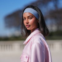 Jamilla Strand wears light blue denim jean headband, gold earrings, light pink short sleeve half zipped oversized Casablanca shirt, outside...