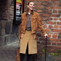 Janka Polliani wears brown cowboy shoes, brown skirt, brown suede jacket, brown striped polo shirt and a brown leather bag with bag charms or...