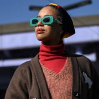 Jasmin Savoy Brown is seen wearing a brown sweater vest, red turtle neck, blue pants, gold boots, Coach bag and lime green sunglasses outside the...