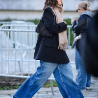 Jeanne Damas wears a beige scarf, a black bag, a black jacket, wide-leg denim jeans / pants, red high heels, outside Stella McCartney , during the...