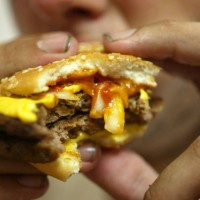 Jeff Baughman bites into his Double Quarterpounder with cheese on July 18, 2002 at a McDonalds in Miami Beach, Florida. The health effects of an...