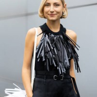 Jenny Walton is seen wearing a white leather bag with fringe, a black leather belt, black high waist trousers and a black knitted tank top...