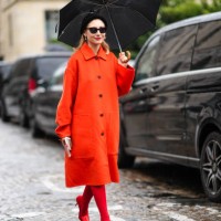 Jenny Walton wears sunglasses, a beret hat, an orange coat, red tights, high heels red shiny pointed shoes, outside Hermes, during the Womenswear...