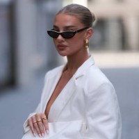 Jess Hunt was seen wearing white shoes, white transparent pants, an oversized white blazer, a white bag, yellow gold earrings and dark Chanel shades...