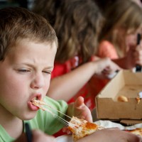 Joe Kendy IV bites into a piece of pizza at Pizza L'Vino, a pizza restaurant that offers home delivery and takeout for pizza, beer and wine, Friday,...