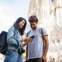jong toeristenpaar dat slimme telefoon in barcelona bekijkt - travel stockfoto's en -beelden