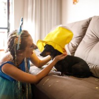 jonge vrouw die een hoed op hond draagt om braziliaans carnaval thuis te vieren - home decoration stockfoto's en -beelden