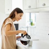 jonge vrouw koffie in beker thuis gieten - coffee stockfoto's en -beelden
