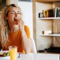 joven sonriente disfrutando del desayuno en casa - food fotografías e imágenes de stock