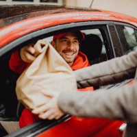 joyful delivery man delivering an order - junk food stock pictures, royalty-free photos & images