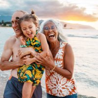 joyful eurasian girl playing at the beach with her grandparents - travel stock pictures, royalty-free photos & images