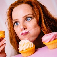 junge frau isst cupcakes mit viel enthusiasmus - food stock-fotos und bilder