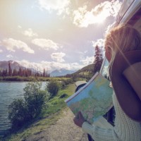 junge frau schaut fahrplan in der nähe von bergsee - travel stock-fotos und bilder