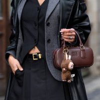 Kacey Lim wears a Miu Miu bag, black leather trench coat, grey jacket, black waistcoat and mini skirt during London Fashion Week February 2025 at the...