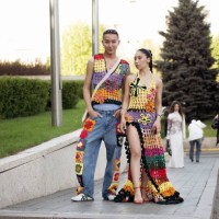 Kanybayev Assylkhan wears blue jeans with knitted colourful details and matching colors knitted vest and Marzhan Sharipova wears long colourful...
