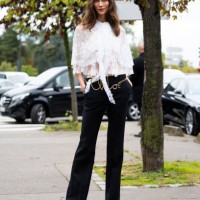 Karlie Kloss wears black and brown platform heeled mules, a Chloé gold belt, mid waist black trousers and a white see-trough lace shirt outside Chloé...