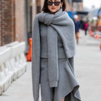 Kate Barlett wears grey knit, asymmetric skirt, boots, white bag outside Michael Kors during New York Fashion Week on February 11, 2025 in New York...