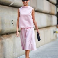 Kate Bartlett wears black sunglasses, white earrings, light pink sleeveless Carolina Herrera shirt, light pink Carolina Herrera midi skirt, black...