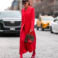 Katya Tolstova wears dark red sunglasses, gold hoop earrings, gold necklaces, bright cherry red blazer jacket, bright cherry red long sleeve sweater,...