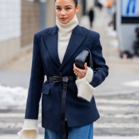 Kelsey Merritt wears navy belted blazer, denim jeans, black bag, creme white turtleneck knit outside Michael Kors during New York Fashion Week on...