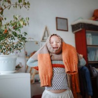 kid girl dresses herself in warm hand-knitted sweater at home. real-life micromoments. - fashion stock pictures, royalty-free photos & images