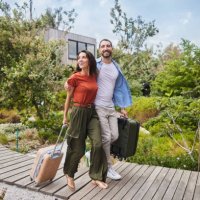 lächelndes paar, das mit koffern in seiner ferienunterkunft ankommt - travel stock-fotos und bilder