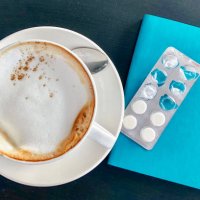 large cappuccino cup next white pills and blue diary - coffee stockfoto's en -beelden