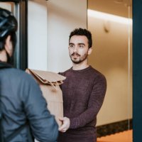 latin man receiving takeaway from a courier - food stock pictures, royalty-free photos & images