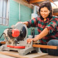 latin woodworker woman using a miter saw on a wooden plank, in her home workshop. - home decoration stock pictures, royalty-free photos & images