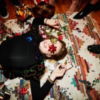 laughing woman lying on floor with bows over eyes during holiday party with friends - home decoration stock pictures, royalty-free photos & images