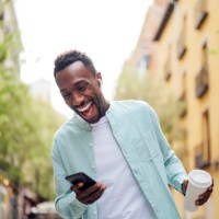 laughing young man with reusable cup using smart phone at street - junk food stock pictures, royalty-free photos & images