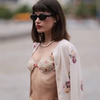 Lea Naumann is seen wearing black oval cay-eye sunglasses from Prada; small silver round earrings; a pearl necklace; a sand-beige two-piece with red...