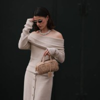 Lea Naumann is seen wearing oval sunglasses with a golden frame, small silver hoop earrings with heart pendants, a pearl necklace, and a silver...