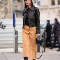 Leia Sfez wears a black leather jacket , a black top, a beige suede midi skirt, a black leather bag, high heels leather boots, outside Chanel, during...