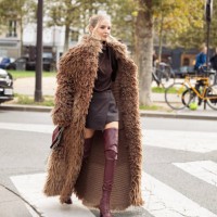 Leonie Hanne wears long over knee burgundy leather boots, burgundy mini skirt, burgundy top, brown fur coat and burgundy bag and sunglasses outside...