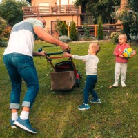 les enfants jouent dans la cour pendant que papa tond l’herbe - garden decoration photos et images de collection