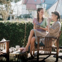 lesbian couple drinking coffee on decking in their garden - garden decoration photos et images de collection