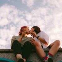 lesbian couple kissing while sitting in the city during summer - fashion stock pictures, royalty-free photos & images