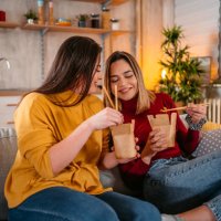 lesbian couple relaxing at home and eating pasta - junk food stock pictures, royalty-free photos & images
