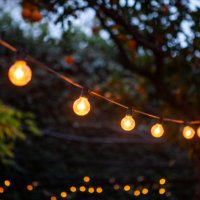 light bulbs hanging from cable against back yard - garden decoration stock pictures, royalty-free photos & images