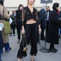 Lily James wears gold earrings, black sheer mesh cropped Chloe top, white black lace bra, gold necklace, black sheer mesh Chloe pants, gold shell...