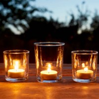 lit tea light candles in glasses in a row on table in garden during sunset - garden decoration stock pictures, royalty-free photos & images
