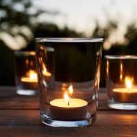 lit tea light candles in glasses on table in garden during sunset - garden decoration stock pictures, royalty-free photos & images