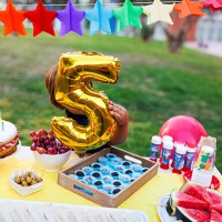 little boy hiding behind golden balloon at laid birthday table - garden decoration stock pictures, royalty-free photos & images