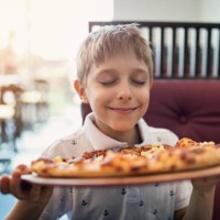little boy smelling pizza in restaurant - food stock pictures, royalty-free photos & images