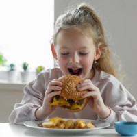 little girl eating a big burger - junk food stock pictures, royalty-free photos & images