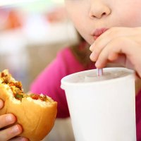 little girl eating burger and drinking soda. - junk food stock pictures, royalty-free photos & images