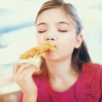 little girl eating fried chicken. - junk food stock pictures, royalty-free photos & images